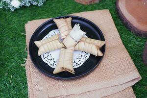 Lepet or Leupeut is a type of snack made from glutinous rice mixed with peanuts, cooked in coconut milk, then wrapped in coconut leaves. Close up view photo