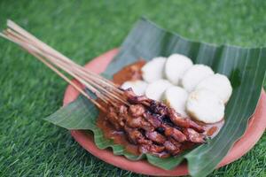 chicken satay on a white plate with peanut sauce photo