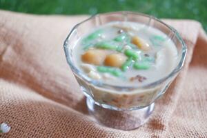 coconut milk in small glass on green grass background photo