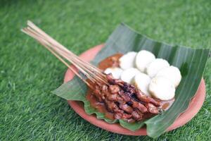 chicken satay on a white plate with peanut sauce photo