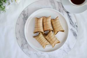 Lepet or Leupeut is a type of snack made from glutinous rice mixed with peanuts, cooked in coconut milk, then wrapped in coconut leaves. Close up view photo