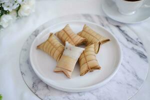 Lepet or Leupeut is a type of snack made from glutinous rice mixed with peanuts, cooked in coconut milk, then wrapped in coconut leaves. Close up view photo