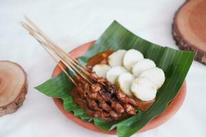 chicken satay on a white plate with peanut sauce photo