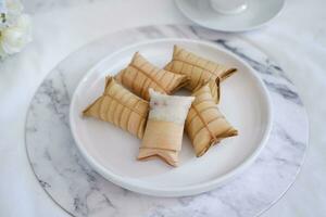 Lepet or Leupeut is a type of snack made from glutinous rice mixed with peanuts, cooked in coconut milk, then wrapped in coconut leaves. Close up view photo
