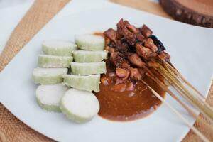 chicken satay on a white plate with peanut sauce photo