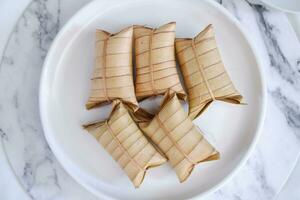 Lepet or Leupeut is a type of snack made from glutinous rice mixed with peanuts, cooked in coconut milk, then wrapped in coconut leaves. Close up view photo