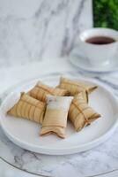 Lepet or Leupeut is a type of snack made from glutinous rice mixed with peanuts, cooked in coconut milk, then wrapped in coconut leaves. Close up view photo