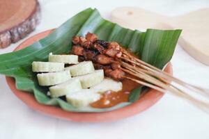 chicken satay on a white plate with peanut sauce photo