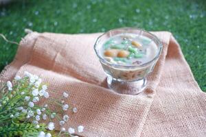 coconut milk in small glass on green grass background photo