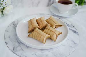 Lepet or Leupeut is a type of snack made from glutinous rice mixed with peanuts, cooked in coconut milk, then wrapped in coconut leaves. Close up view photo