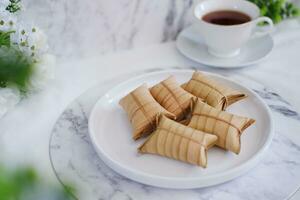 Lepet or Leupeut is a type of snack made from glutinous rice mixed with peanuts, cooked in coconut milk, then wrapped in coconut leaves. Close up view photo