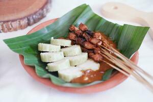chicken satay on a white plate with peanut sauce photo
