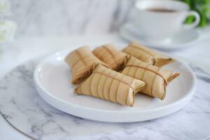 Lepet or Leupeut is a type of snack made from glutinous rice mixed with peanuts, cooked in coconut milk, then wrapped in coconut leaves. Close up view photo