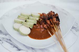chicken satay on a white plate with peanut sauce photo