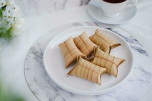 Lepet or Leupeut is a type of snack made from glutinous rice mixed with peanuts, cooked in coconut milk, then wrapped in coconut leaves. Close up view photo