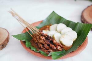 chicken satay on a white plate with peanut sauce photo