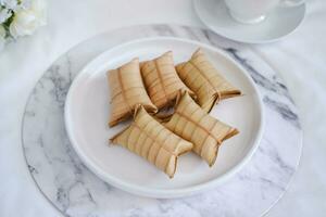 Lepet or Leupeut is a type of snack made from glutinous rice mixed with peanuts, cooked in coconut milk, then wrapped in coconut leaves. Close up view photo