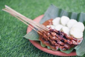 chicken satay on a white plate with peanut sauce photo