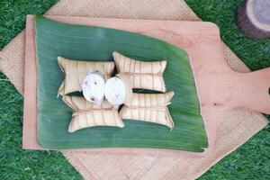Lepet or Leupeut is a type of snack made from glutinous rice mixed with peanuts, cooked in coconut milk, then wrapped in coconut leaves. Close up view photo