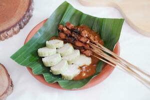 chicken satay on a white plate with peanut sauce photo