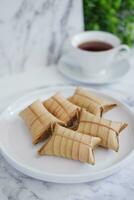 Lepet or Leupeut is a type of snack made from glutinous rice mixed with peanuts, cooked in coconut milk, then wrapped in coconut leaves. Close up view photo