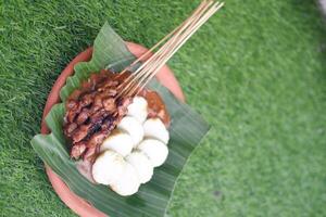 chicken satay on a white plate with peanut sauce photo