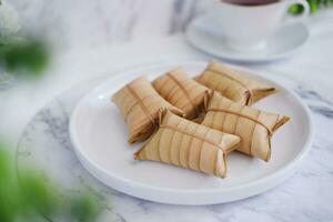 Lepet or Leupeut is a type of snack made from glutinous rice mixed with peanuts, cooked in coconut milk, then wrapped in coconut leaves. Close up view photo