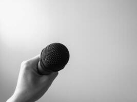 Close-up microphone in left hand of singer at concert with copy space, Singing concept, Black and white. photo