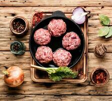 Raw meatball over wooden background photo