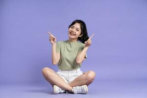 Portrait of beautiful asian girl sitting on purple background photo