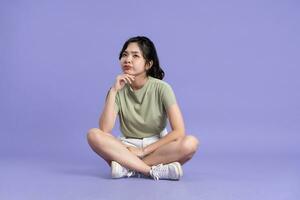 Portrait of beautiful asian girl sitting on purple background photo