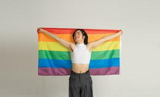 imagen de asiático gay hombre participación un arco iris bandera con confianza posando en un blanco antecedentes foto