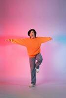 Image of a young Asian person dancing on a neon colored background photo