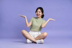 retrato de hermosa asiático niña sentado en púrpura antecedentes foto