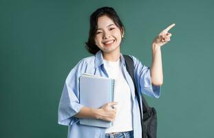 Portrait of a beautiful Asian student on a green background photo