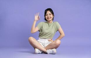 Portrait of beautiful asian girl sitting on purple background photo