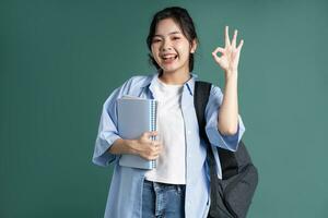 Portrait of a beautiful Asian student on a green background photo