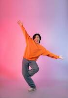 Image of a young Asian person dancing on a neon colored background photo