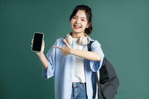 Portrait of a beautiful Asian student on a green background photo