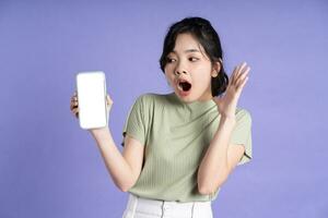 Portrait of beautiful asian woman using smartphone on purple background photo