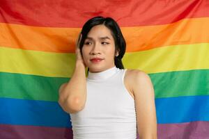 Image of Asian gay man holding a rainbow flag confidently posing on a white background photo