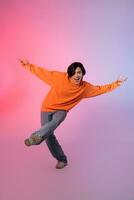 Image of a young Asian person dancing on a neon colored background photo