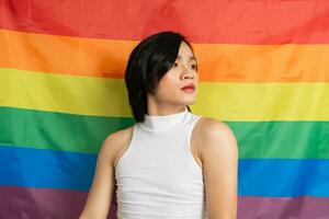 Image of Asian gay man holding a rainbow flag confidently posing on a white background photo