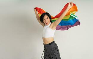 Image of Asian gay man holding a rainbow flag confidently posing on a white background photo