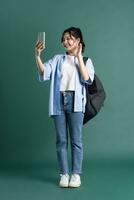 retrato de un hermosa asiático estudiante en un verde antecedentes foto