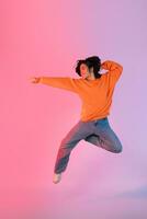 Image of a young Asian person dancing on a neon colored background photo