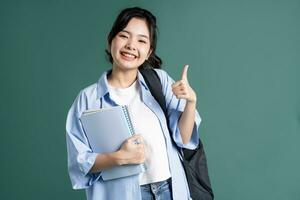 Portrait of a beautiful Asian student on a green background photo