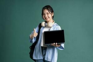 retrato de un hermosa asiático estudiante en un verde antecedentes foto