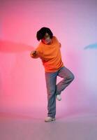 Image of a young Asian person dancing on a neon colored background photo