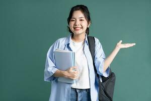 Portrait of a beautiful Asian student on a green background photo